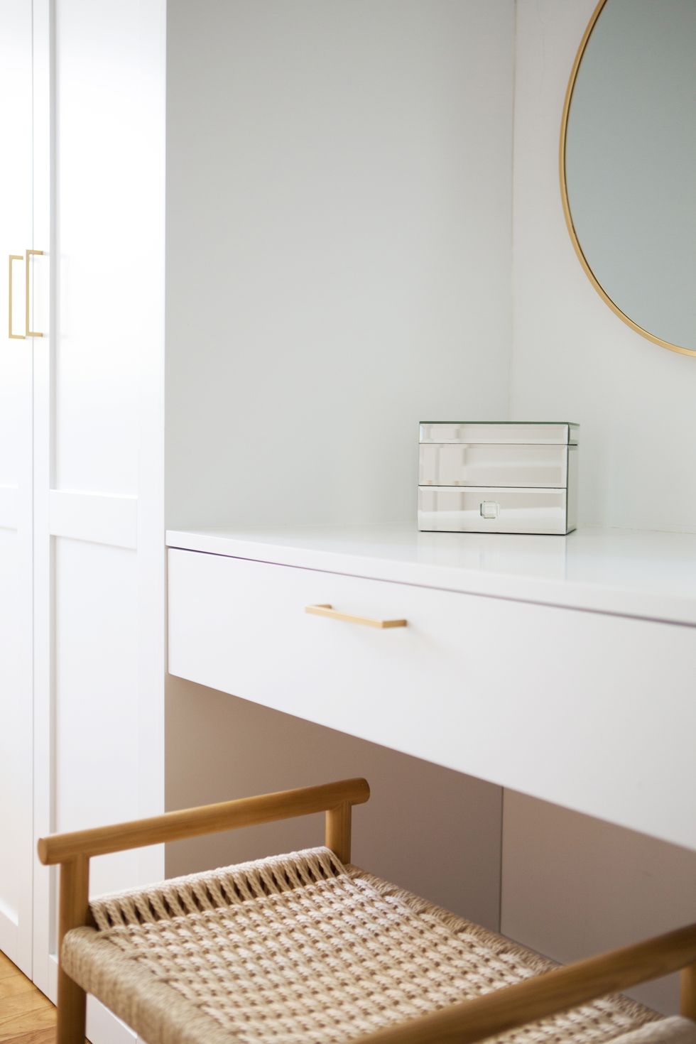tocador blanco con espejo redondo con marco de latón y silla de fibras