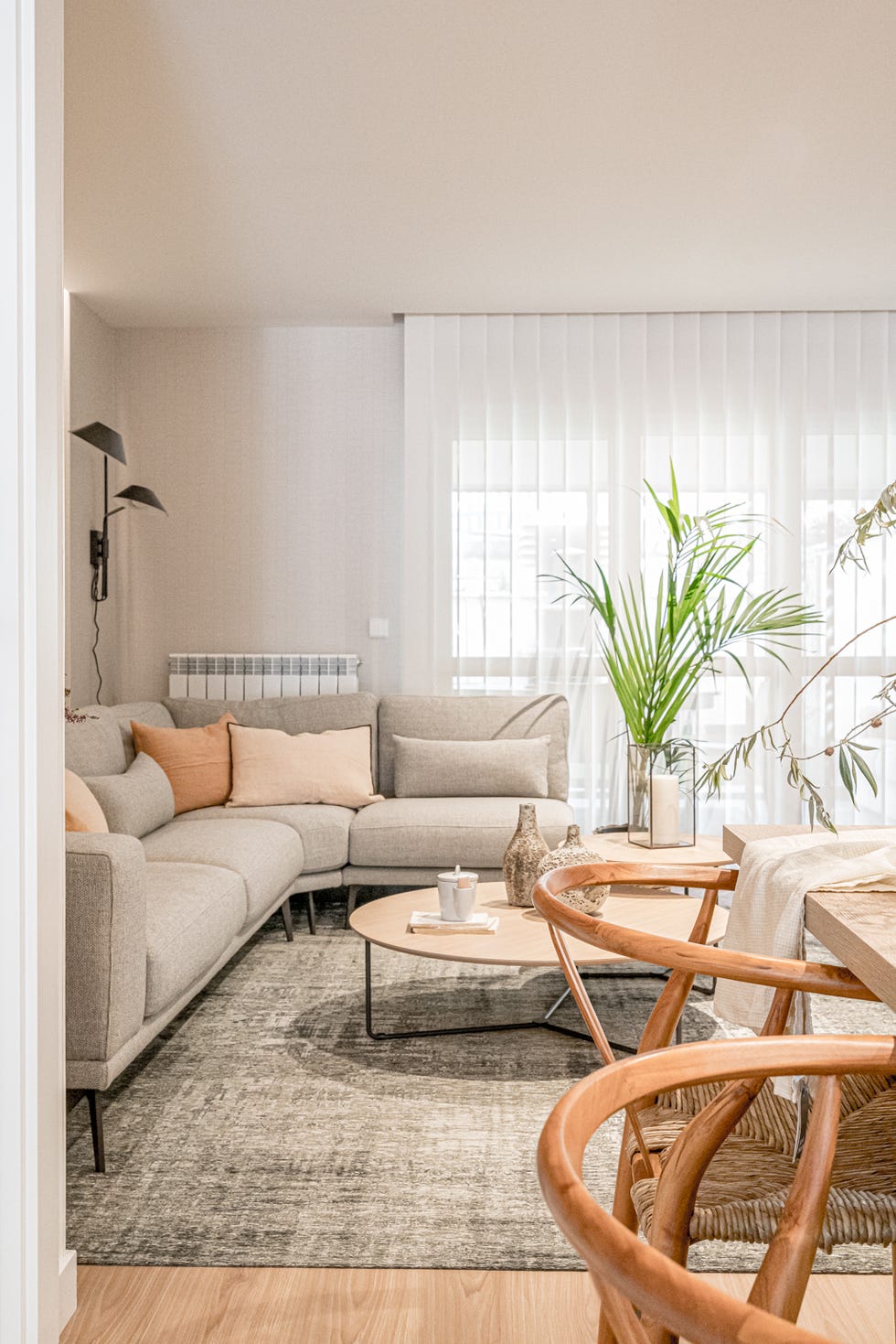 salón con sofá esquinero gris y mesas nido de madera redondas