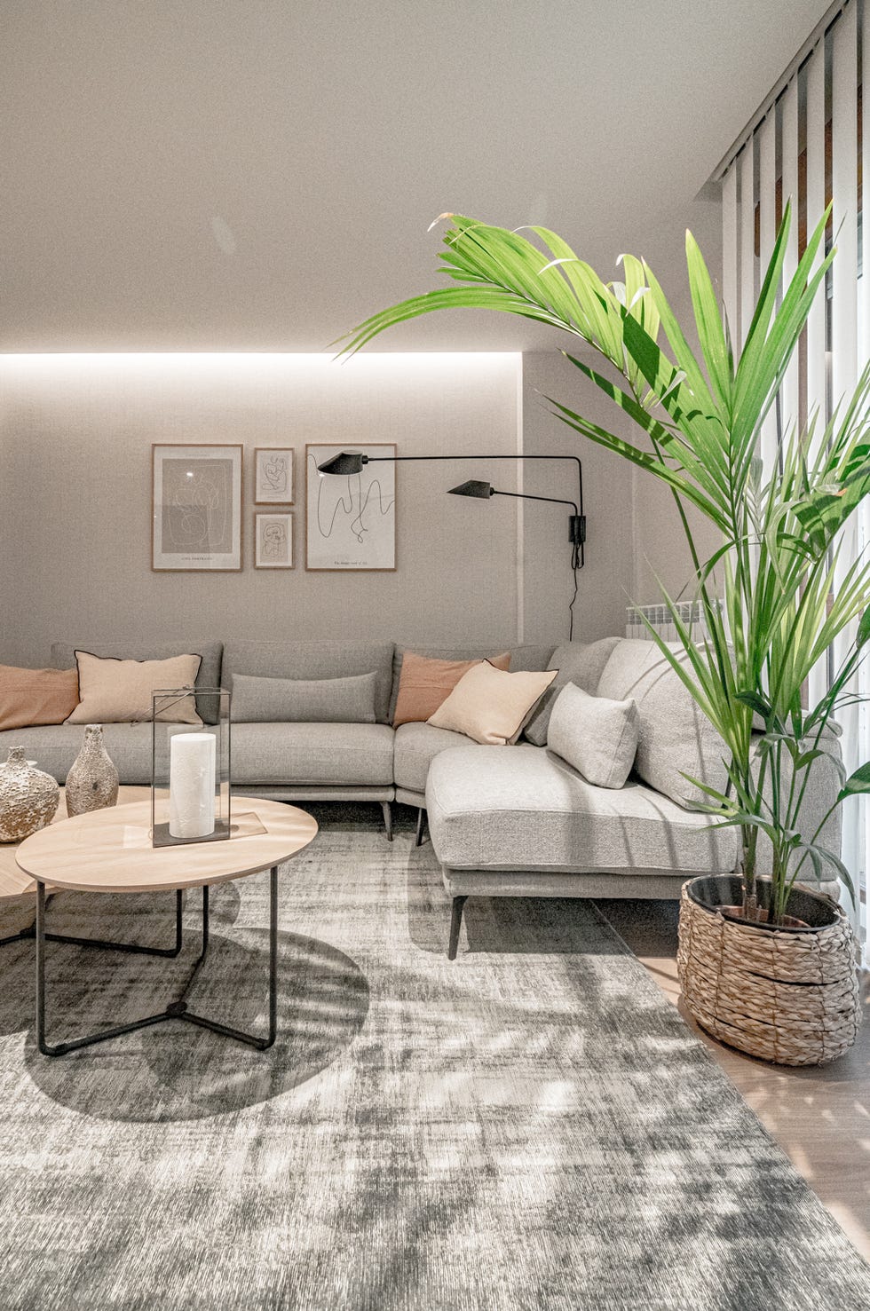 salón con sofá esquinero gris y mesas nido de madera redondas