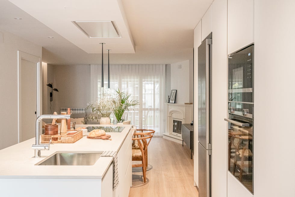 cocina blanca abierta con isla central y comedor de madera