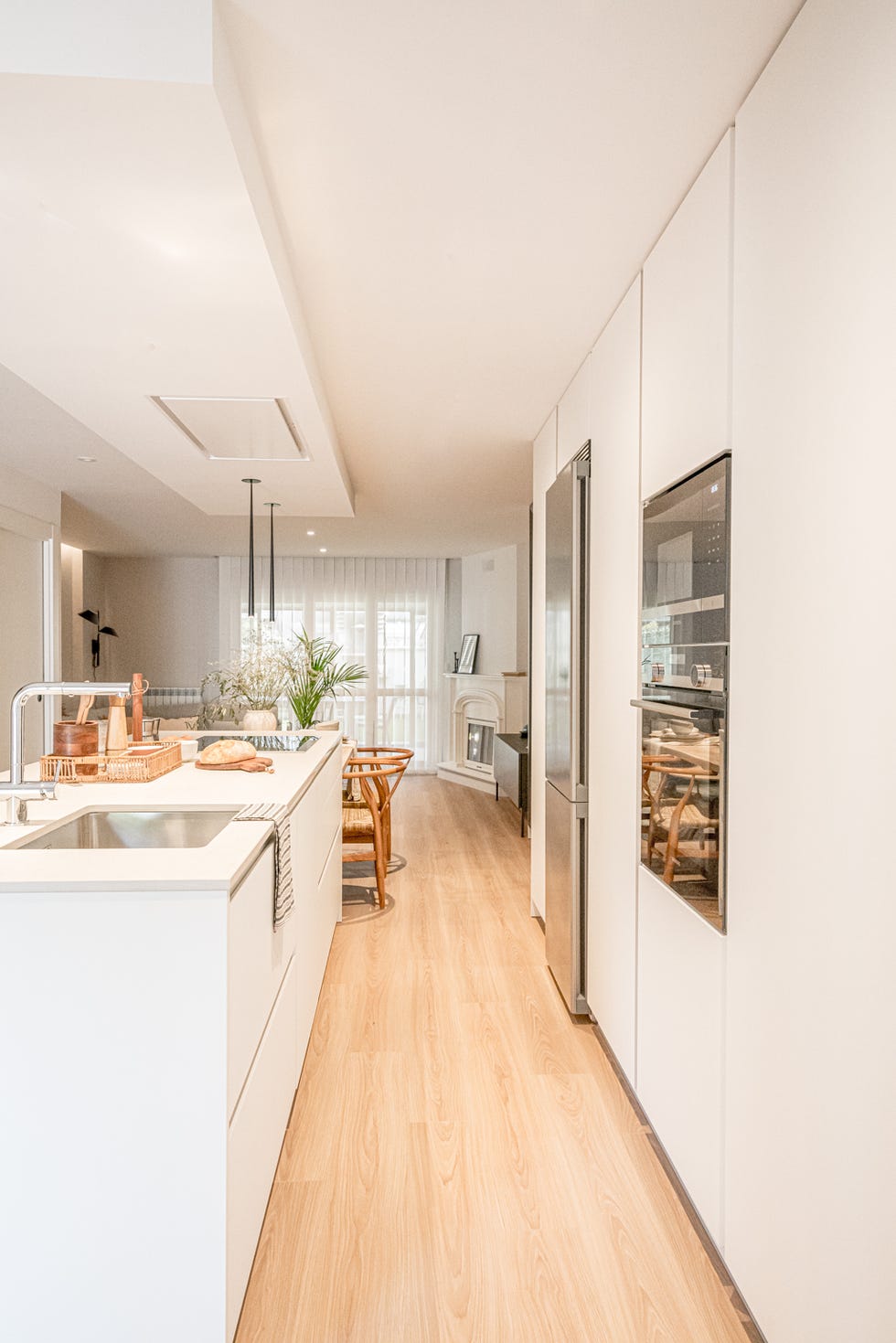 cocina blanca abierta con isla central y comedor de madera