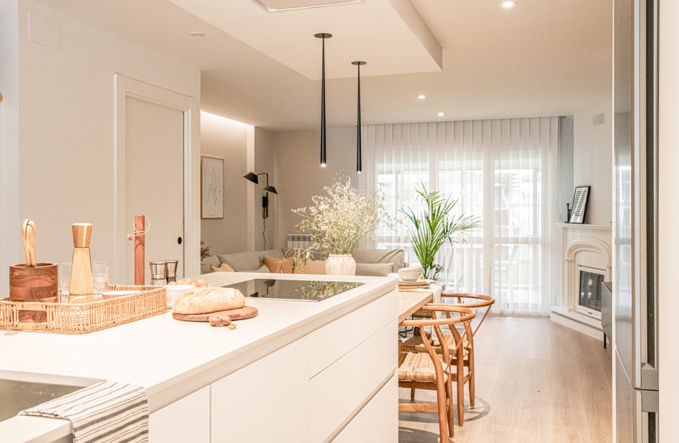 cocina blanca abierta con isla central y comedor de madera