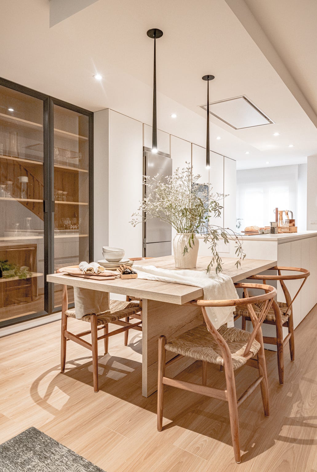 cocina blanca abierta con isla central y comedor de madera