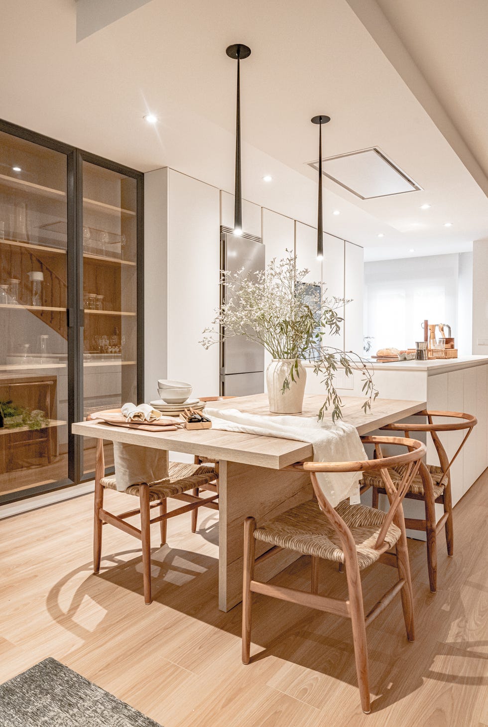 cocina blanca abierta con isla central y comedor de madera
