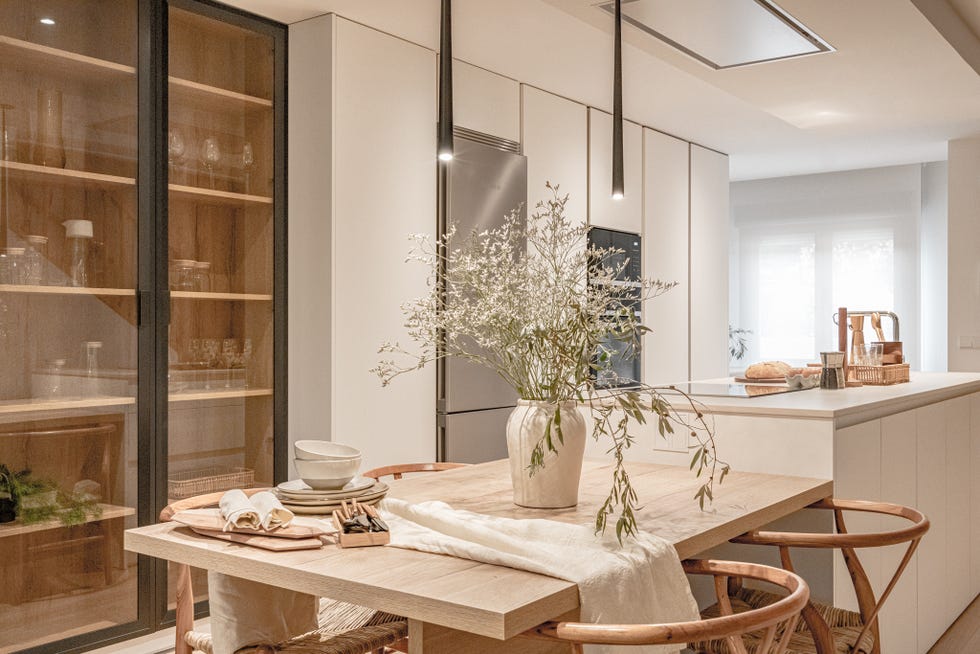 cocina blanca abierta con isla central y comedor de madera