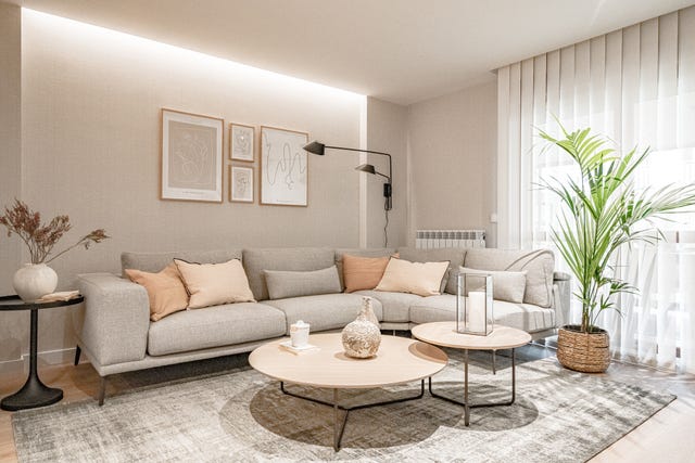 salón con sofá esquinero gris y mesas nido de madera redondas