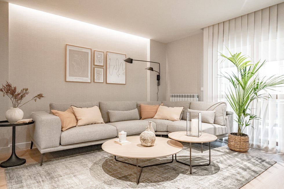 salón con sofá esquinero gris y mesas nido de madera redondas