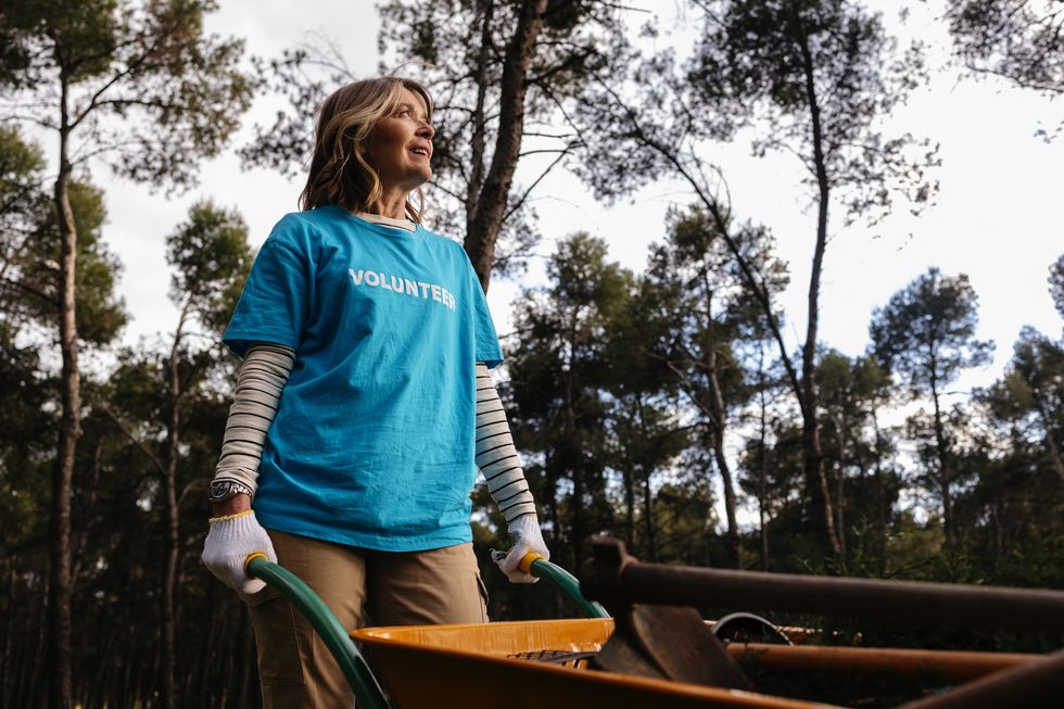 volunteer pushing wheelbarrow in a forest while looking up