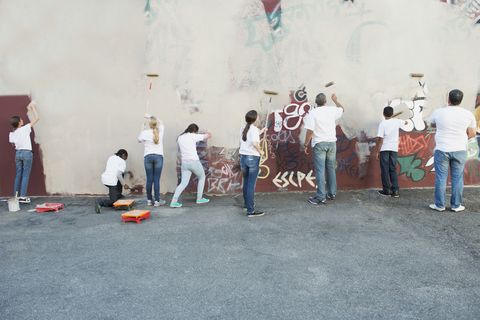 volunteers painting over graffiti wall