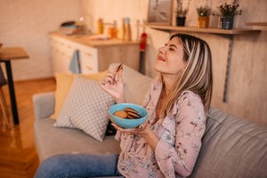 een vrouw eet koekjes op de bank