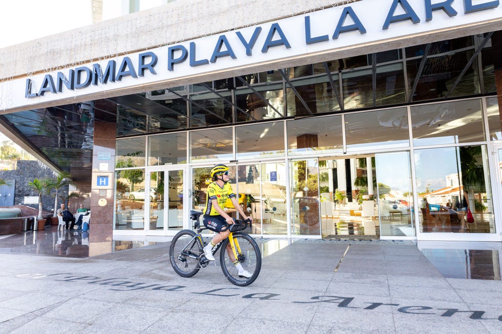 a cyclist in a yellow jersey near the entrance of a hotel