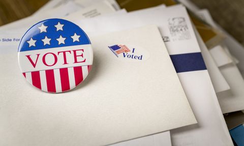 vote pin on a pile of mail in ballots