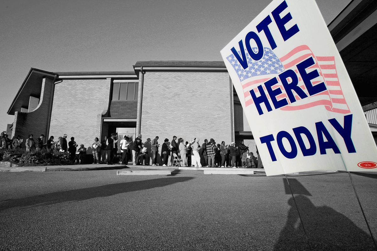 a black and white photo of people lined up to vote with a sign that says vote here today in color