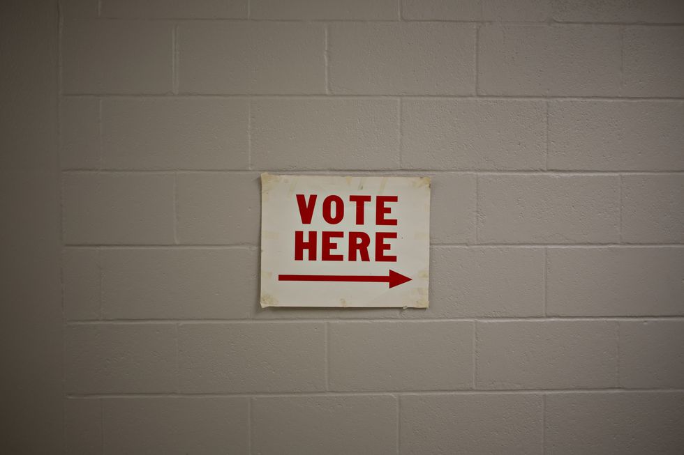 a "vote here" sign hangs in the hallway at a polling location