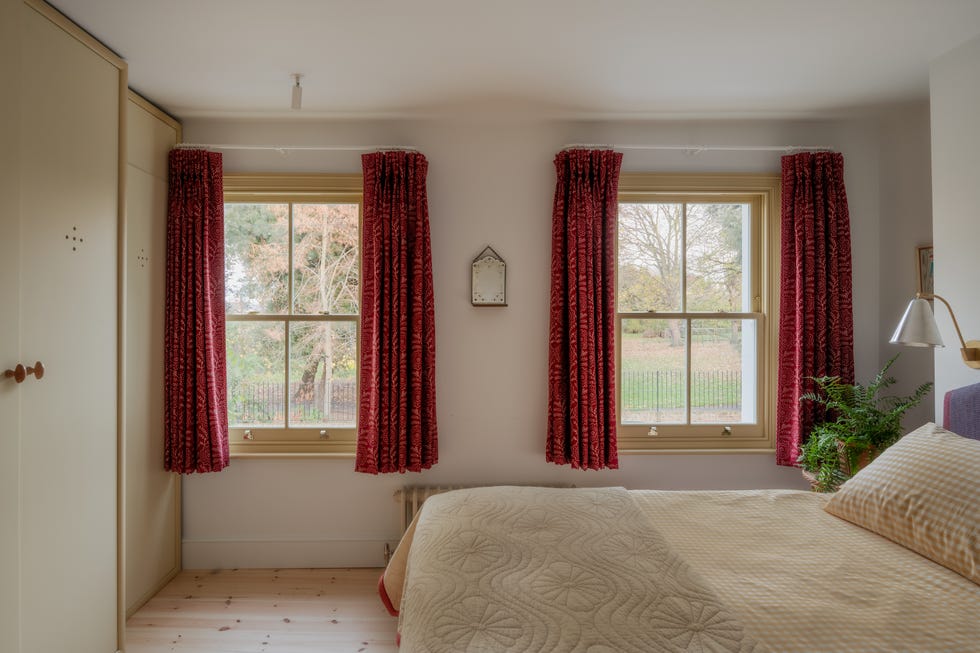 a bedroom with yellow window frames and short curtains