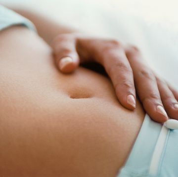 vrouw heeft hand op haar buik omdat ze graag zwanger wil worden en probeert haar vruchtbare dagen te herkennen
