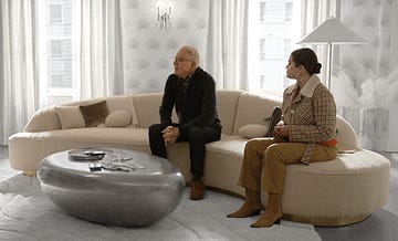 steve martin and selena gomez sit on a curved white sofa in season 3 of only murders in the building