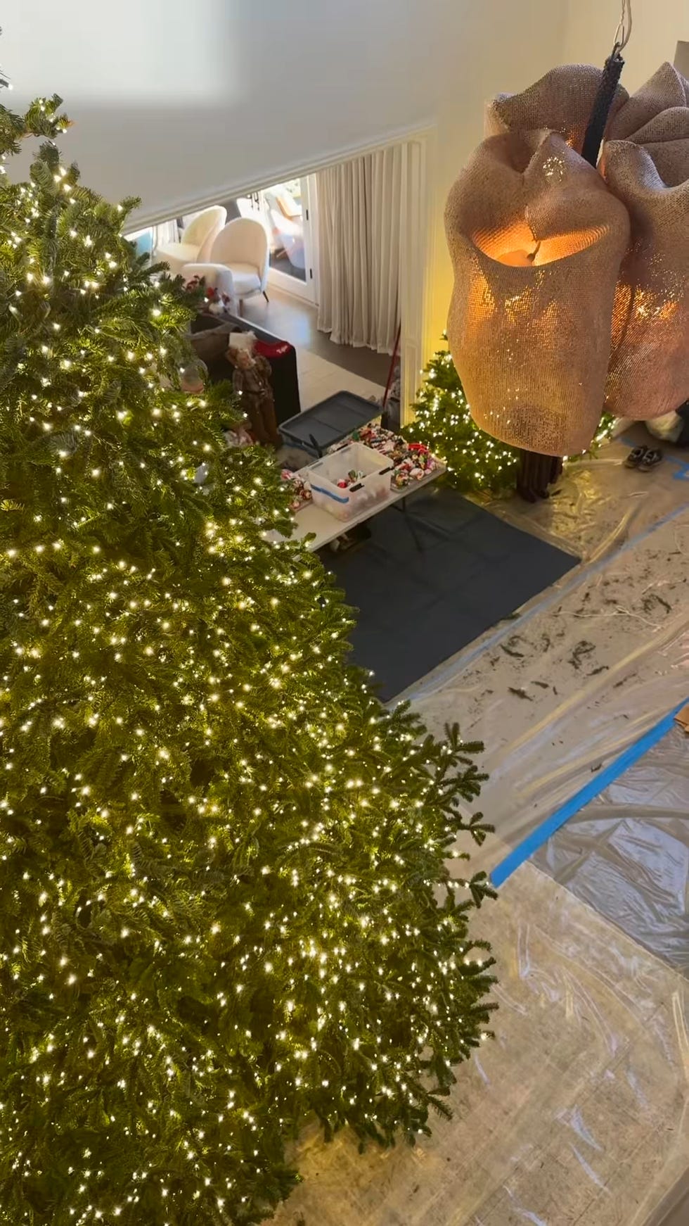 two decorated christmas trees with lights a chandelier and a table with holiday items