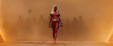 lady deadpool walking on a dusty battlefield