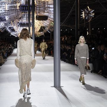 a couple of women walking down a runway with a crowd watching