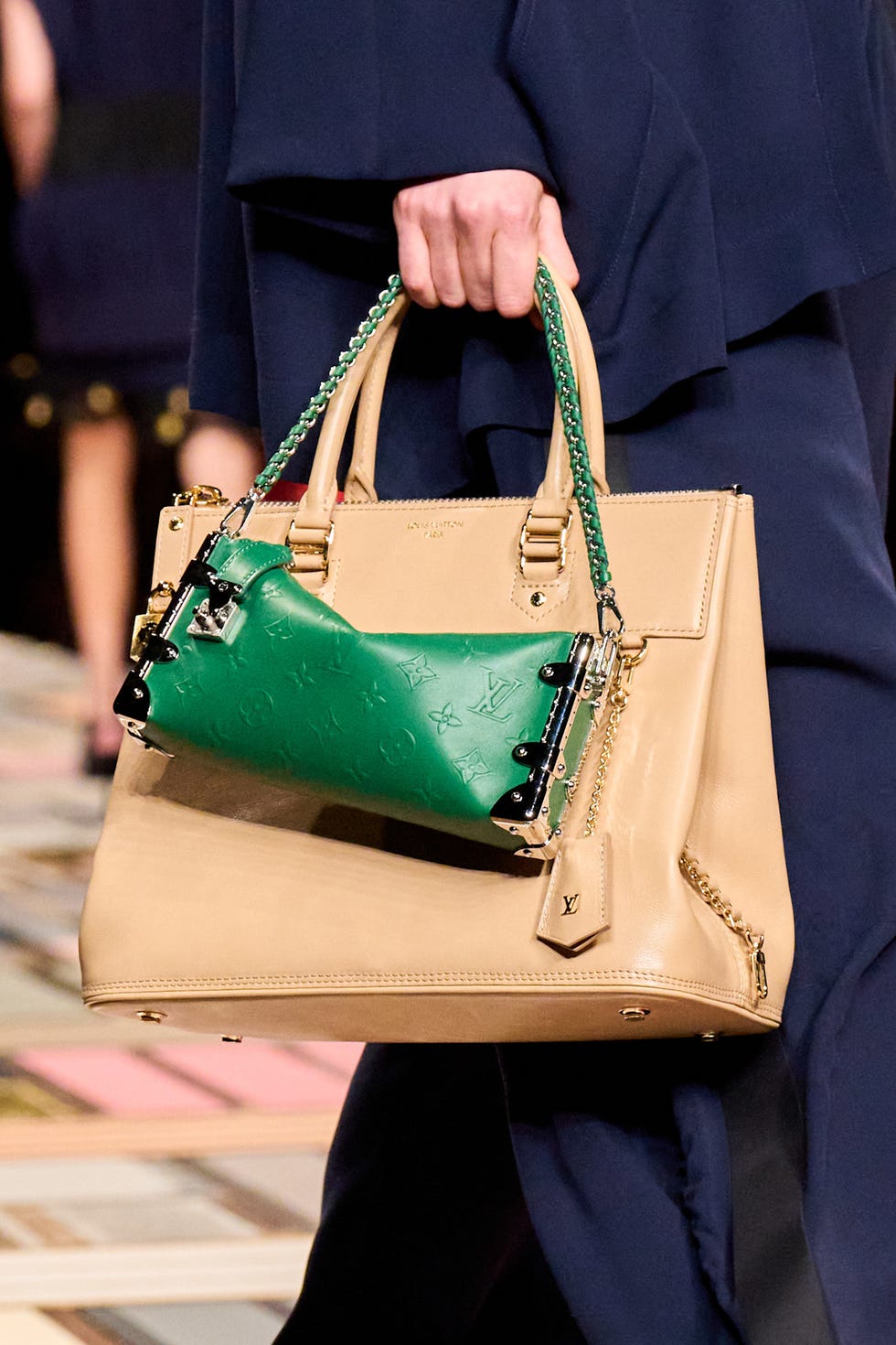 Two designer handbags being held by a model