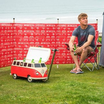 a man sitting in a chair next to a small vw bus cooler
