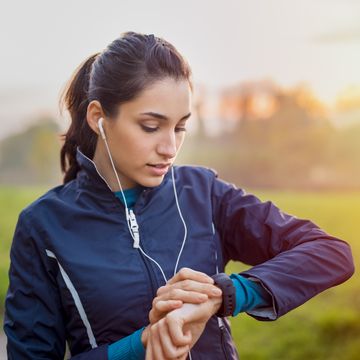 een vrouw kijkt op haar horloge tijdens het hardlopen