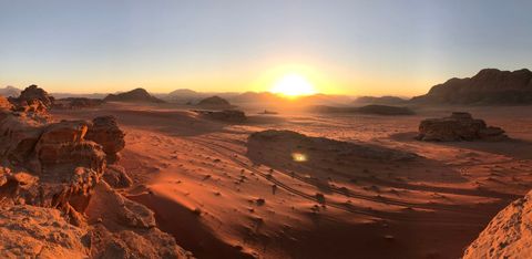 Ik klom op de rotsen om de laatste zonnestralen van de dag te zien schijnen op de roodgekleurde woestijn