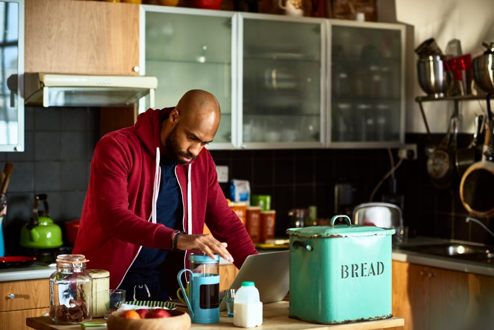 waist up of man with shaved head making fresh coffee in kitchen