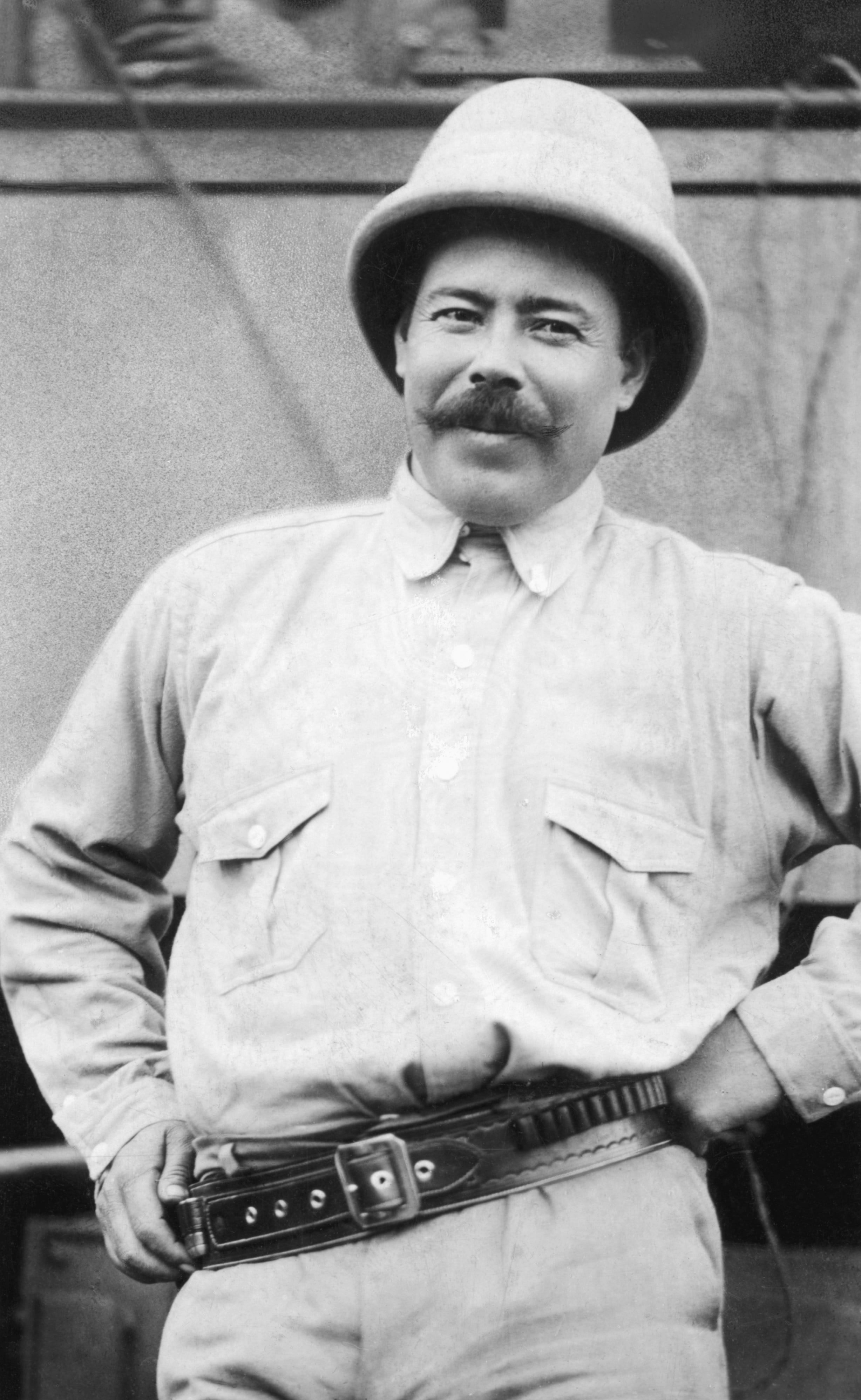 pancho villa smiling for a photo while holding a belt with ammunition around his waist