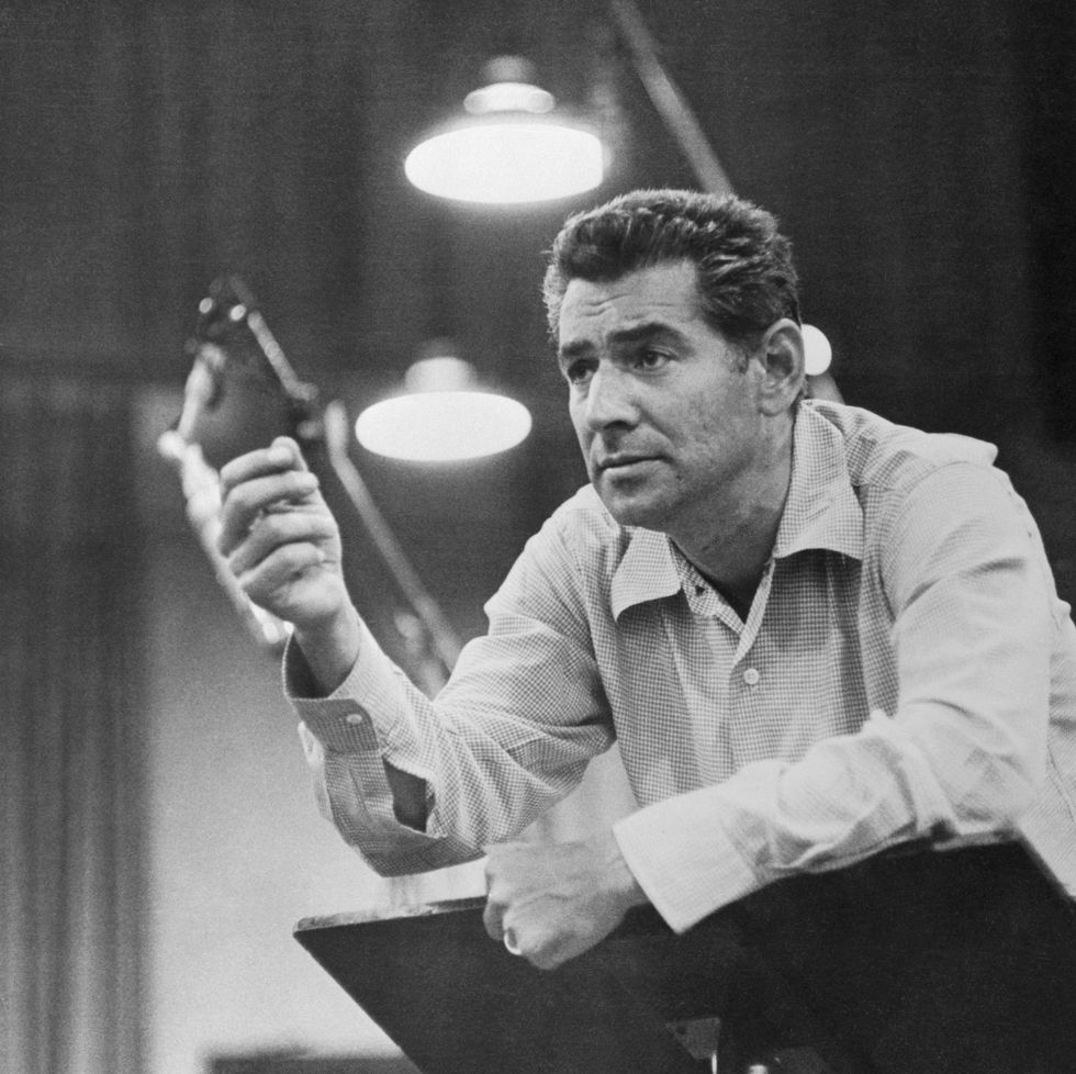 11/18/1957 waist up portrait of leonard bernstein, conductor, with hand raised.