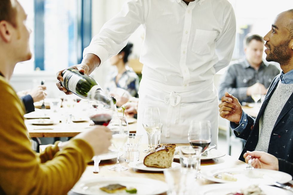waiter pouring wine for couples in restaurant