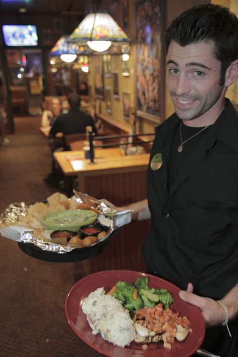 A waiter serving food in Applebee's Neighborhood Grill and Bar.