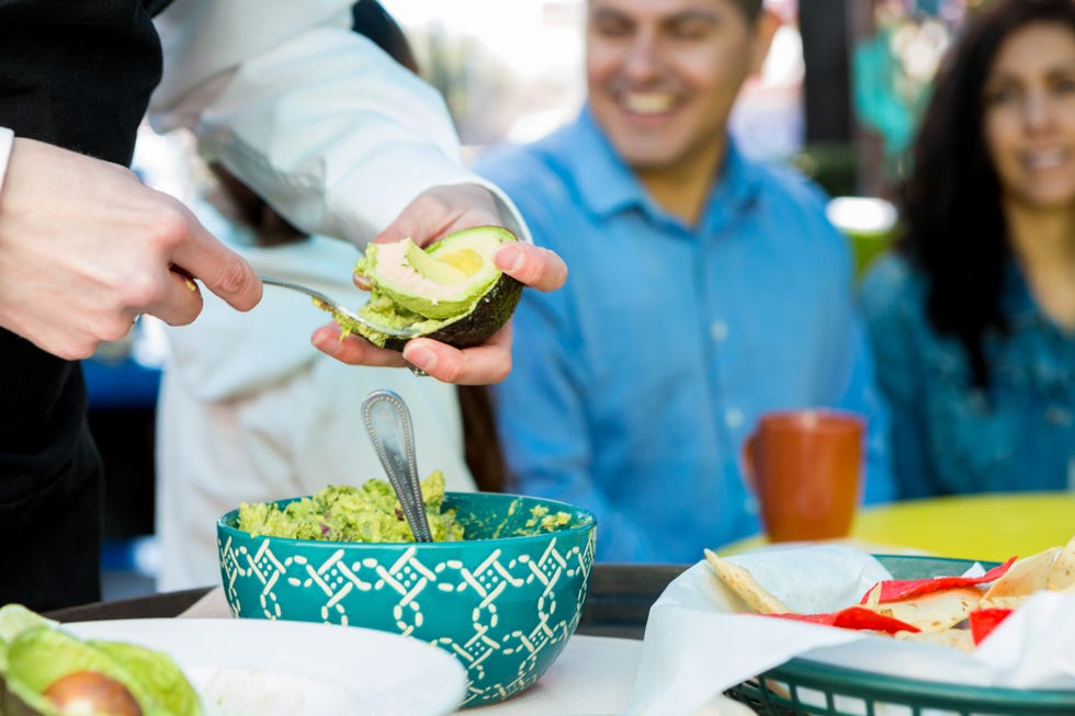 waitress making table side guacamole for customers in restaurant