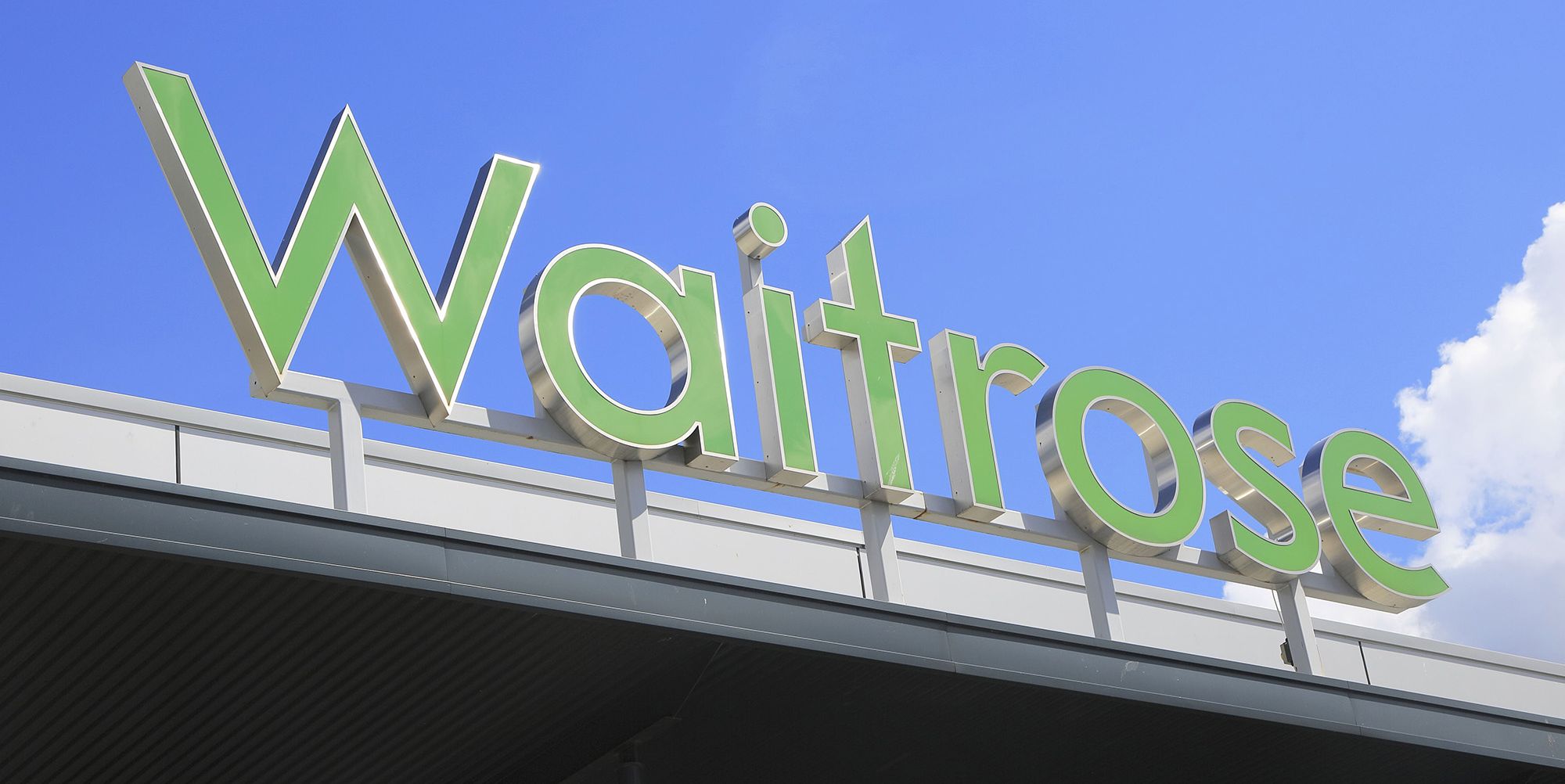 green waitrose supermarket shop sign against blue sky, ipswich, suffolk, england