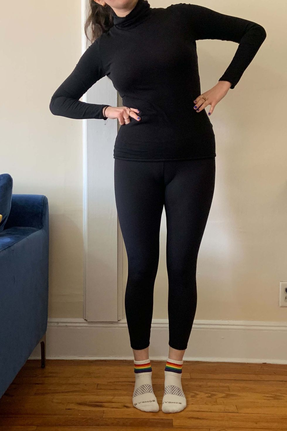 a woman wearing black leggings and a black turtle neck bending to the side to demonstrate how to measure your waist