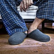 a man's legs and feet wearing blue pajama pants and gray slippers