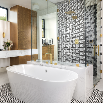 walkin shower ideas, black and white geometric pattern in the walk in shower with a white tub and gold fixtures