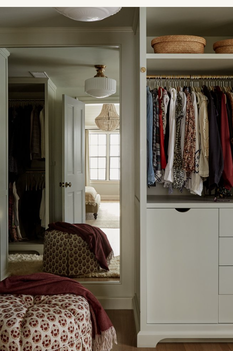 a closet with a mirror and ottoman