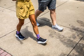 a man and woman walking on a sidewalk in walking shoes