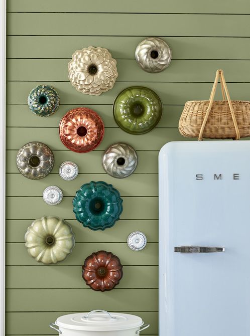 a collection of colorful bundt pans is hung in a kitchen