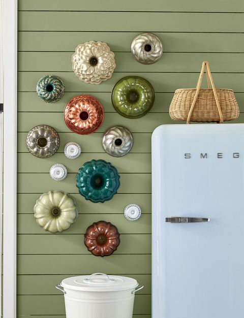 a collection of colorful bundt pans is hung in a kitchen