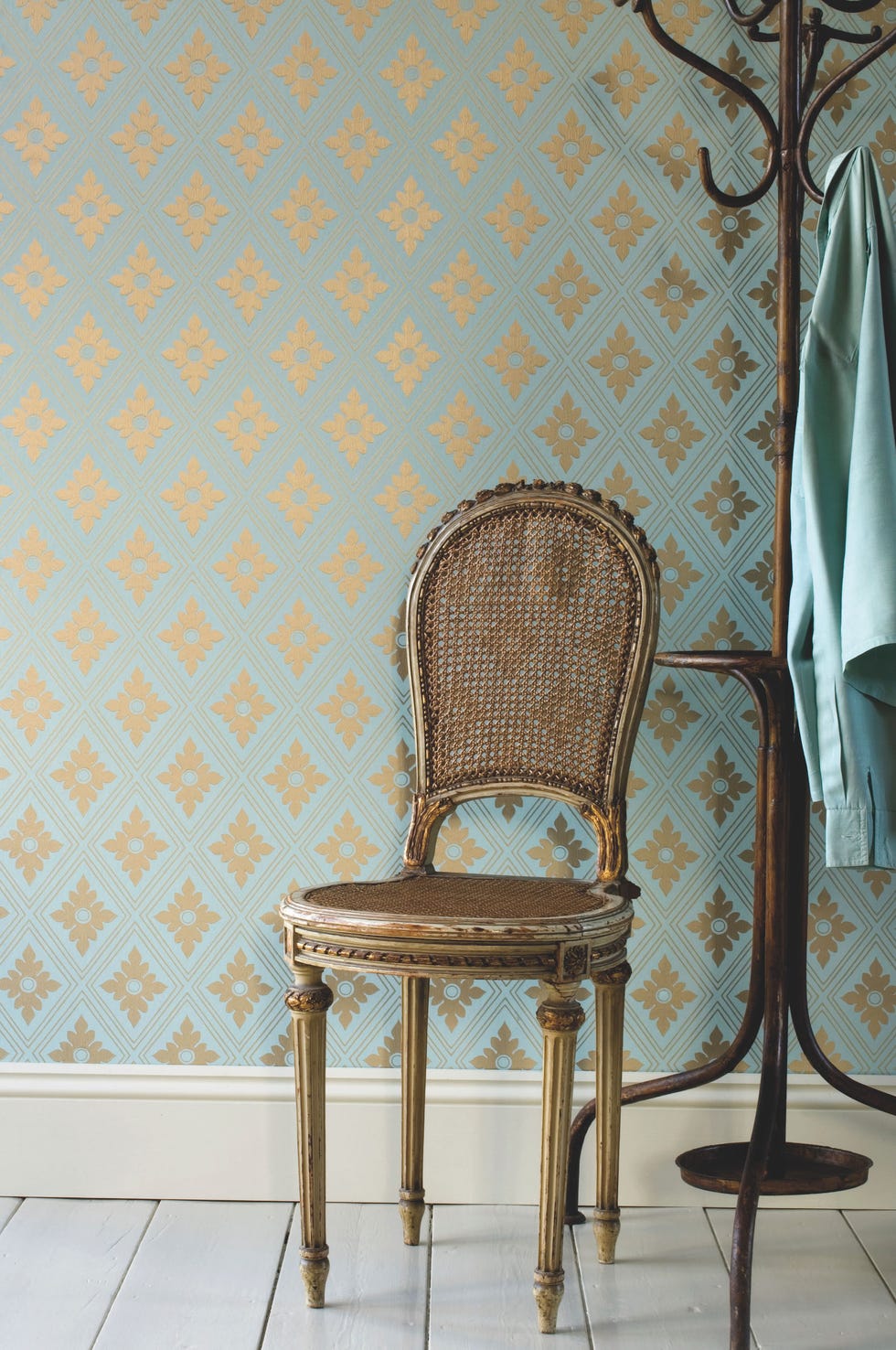 a chair and coat rack in front of geometric wallpaper