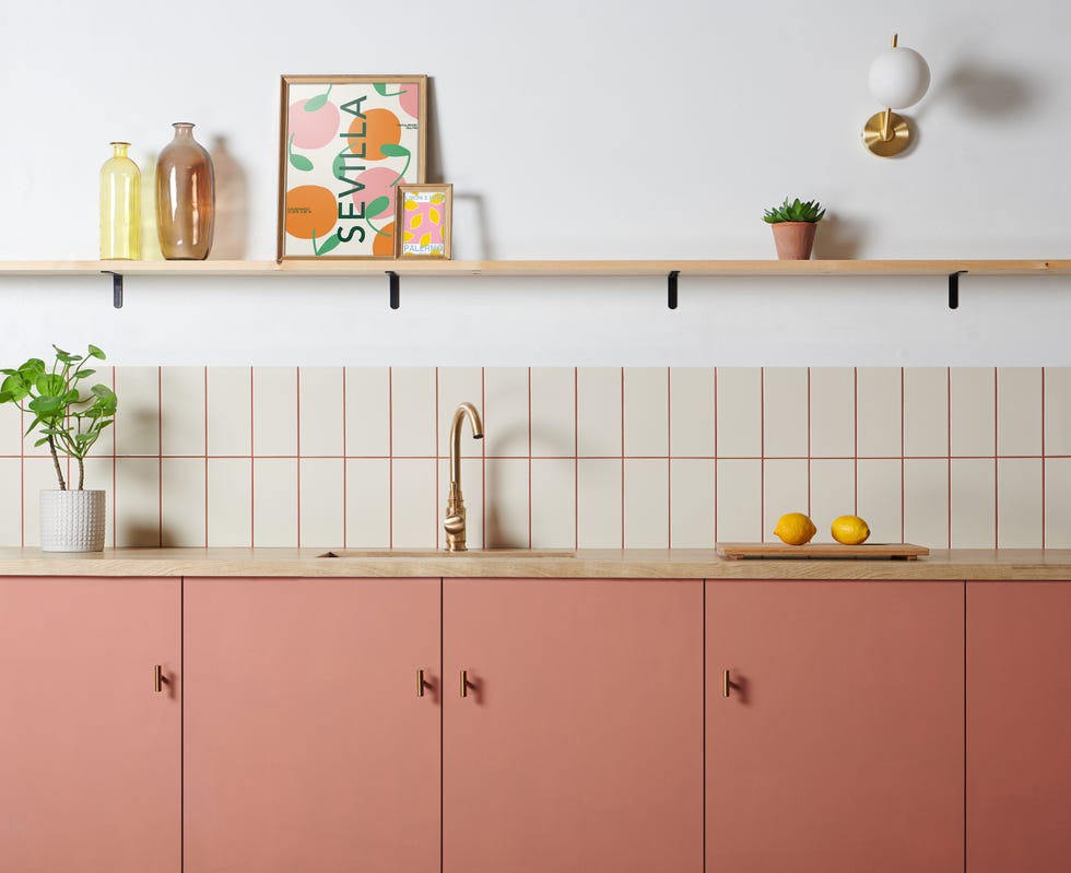 a white kitchen with white kitchen wall tiles, terracotta grouting and pink cabinets