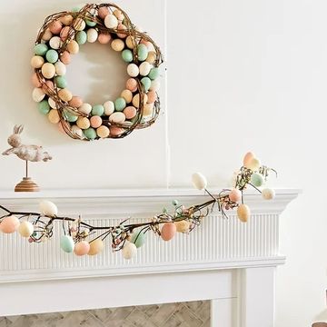 a fireplace decorated for easter with an egg garland and wreath