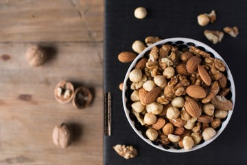 walnuts, almonds and hazelnuts in a bowl on black background