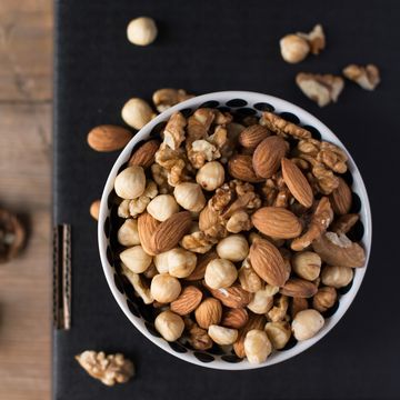 walnuts, almonds and hazelnuts in a bowl on black background