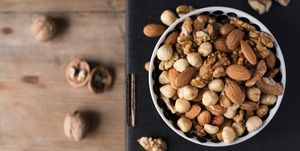 walnuts, almonds and hazelnuts in a bowl on black background