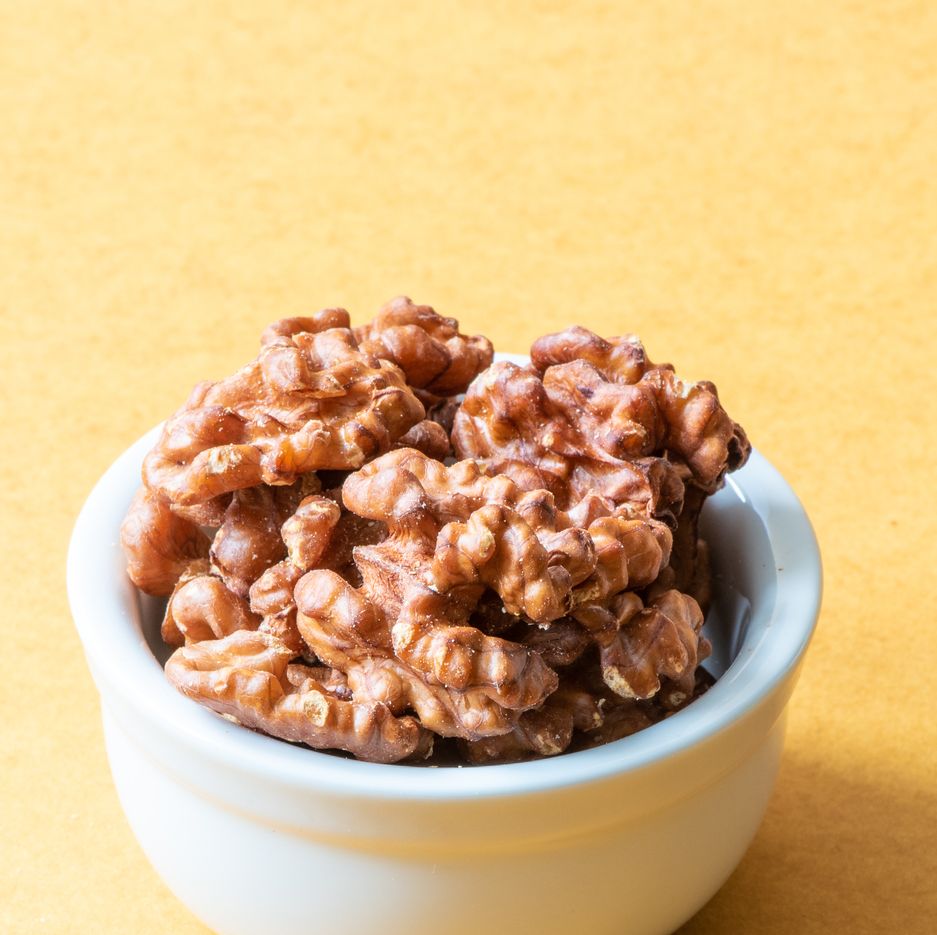 a white bowl of walnuts on a yellow background,  a good housekeeping pick for a healthy weight loss food