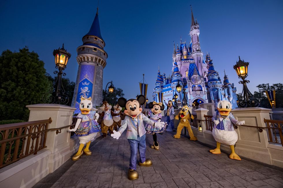 mickey mouse and friends wearing their 50th anniversary shimmering fashions while posing in front of cinderella castle at magic kingdom park